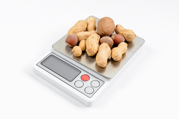 Foto mistura de nozes em balanças eletrônicas com fundo branco. conceito de dieta e perda de peso.