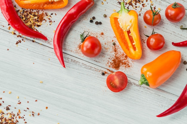 Mistura de pimentão fresco colorido, tomate cereja e especiarias na mesa de madeira branca simulada