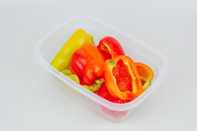 Mistura de pimentos vermelhos, verdes e amarelos biológicos num recipiente Armazenamento de legumes Organização do espaço na cozinha