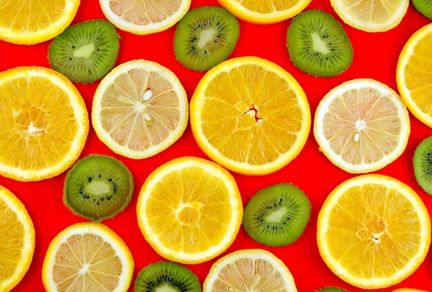 Mistura de textura e frutas de fundo: limão, laranja, kiwi em fundo vermelho.