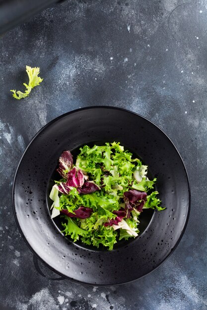 Misture folhas frescas de rúcula, alface, espinafre, beterraba para salada em um fundo de pedra escuro. foco seletivo.