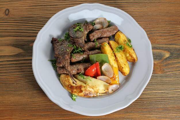 Foto misture kofta kabab e costela de cordeiro com legumes de batata, tomate e cebola servidos em prato isolado na mesa, vista da comida árabe