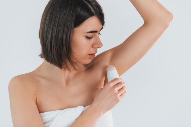 Mit Ball-Deodorant Junge Brünette ist drinnen vor weißem Hintergrund