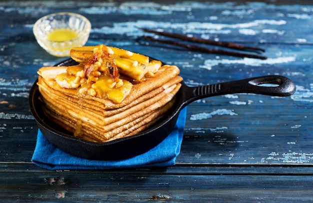 Mit Bananen, Honig und Nüssen in einer gusseisernen Pfanne karamellisierte Pfannkuchen Dünne Pfannkuchen oder Crêpes