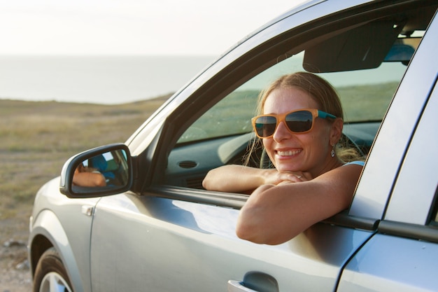 Mit dem Auto fahren. Glückliches Mädchen mit Brille schaut aus dem Auto