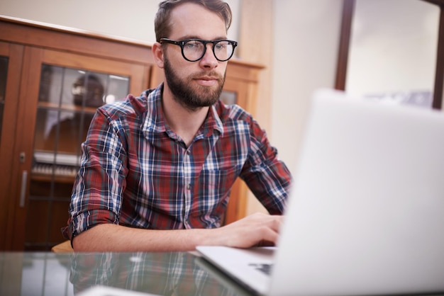 Mit der neuesten Technologie Aufnahme eines hübschen jungen Hipsters, der an einem Laptop arbeitet