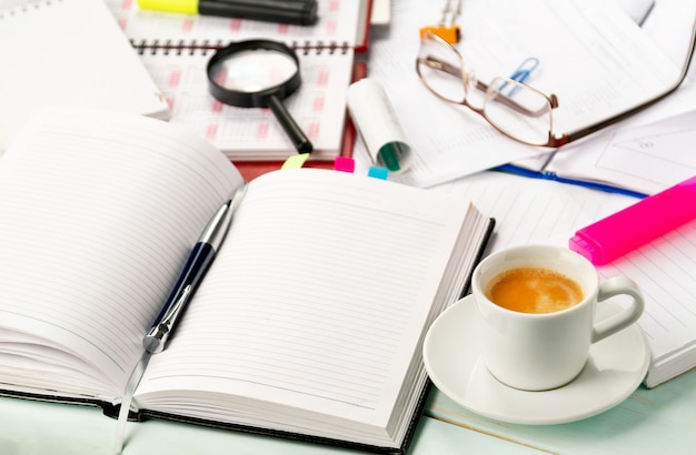 Mit Dokumenten arbeiten. Notizbuch, Stift, Notizbuch, Taschenrechner, Finanzdokumente, eine Tasse Cappuccino-Kaffee auf dem Tisch.