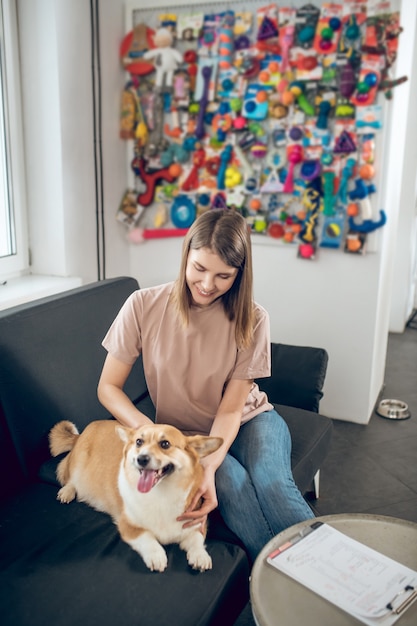 Mit einem Hund. Weibliche Haustierbesitzerin, die mit ihrem Hund auf einem Sofa sitzt