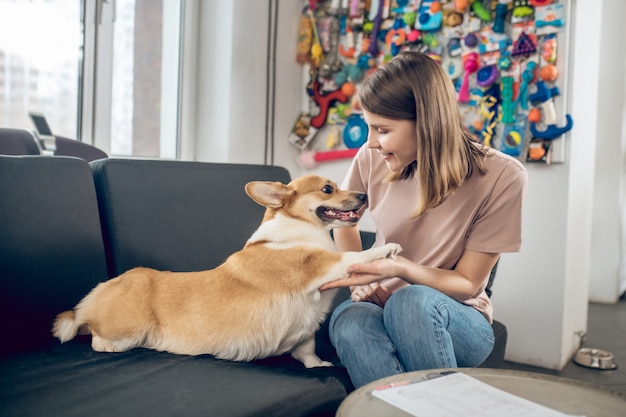 Mit einem Hund. Weibliche Haustierbesitzerin, die mit ihrem Hund auf einem Sofa sitzt