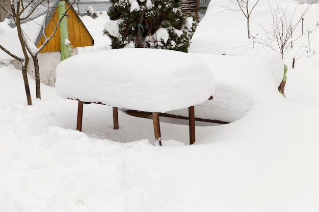 Mit einer dicken Schneeschicht bedeckte Gegenstände auf der Straße im Winter, große Schneefälle in den Dörfern im Winter