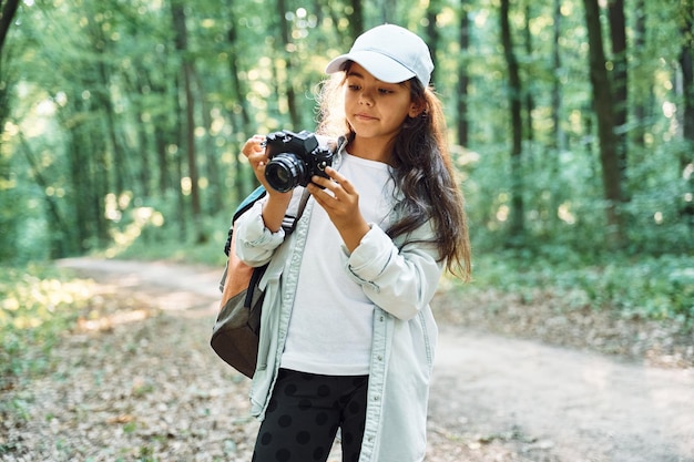 Mit einer professionellen Kamera ist das Mädchen im Sommer tagsüber im Wald und entdeckt neue Orte