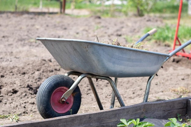 Mit Erde oder Kompost gefüllte Gartenschubkarre am Hof Saisonale Gartenreinigung vor dem Herbst