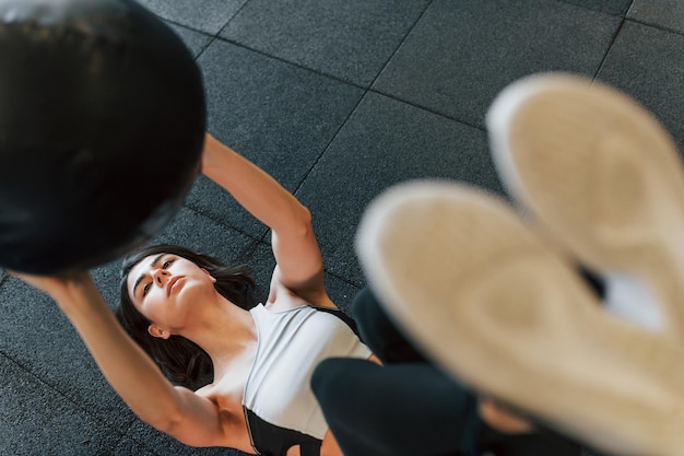 Mit Fitnessball Frau in sportlicher Kleidung mit schlankem Körpertyp ist im Fitnessstudio