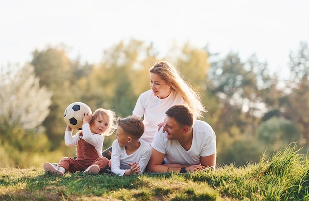 Mit Fußball Glückliche Familie im Freien in der Nähe des Waldes liegend Mit Tochter und Sohn