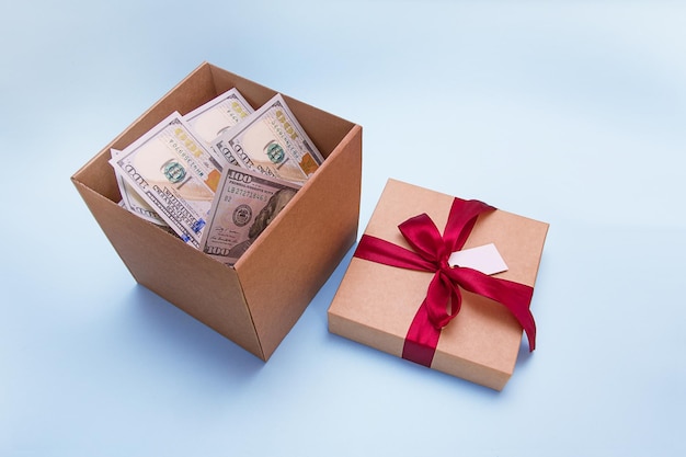 Mit Geld gefüllte Geschenkbox, daneben ein Deckel, der mit einem Satinband und einem leeren Etikett zugebunden ist