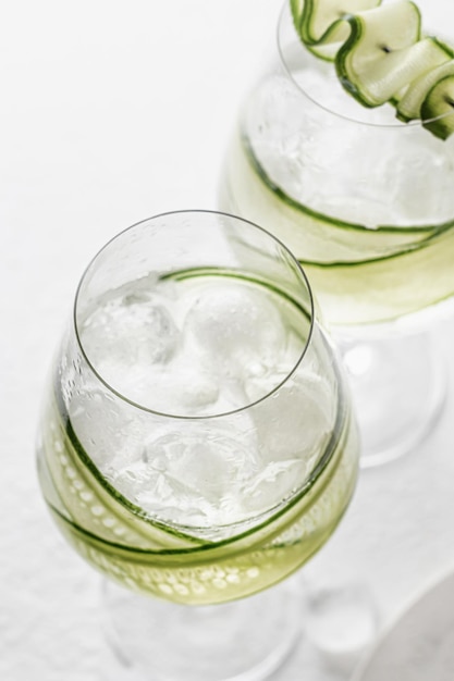 Foto mit gurken angereichertes detox-wasser in gläsern mit eis. hausgemachte aromatisierte limonade auf weißem grau
