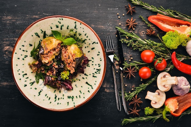 Mit Kalbsmozzarella und Tomaten gefüllte Aubergine Draufsicht auf schwarzem Holzhintergrund Kopierbereich
