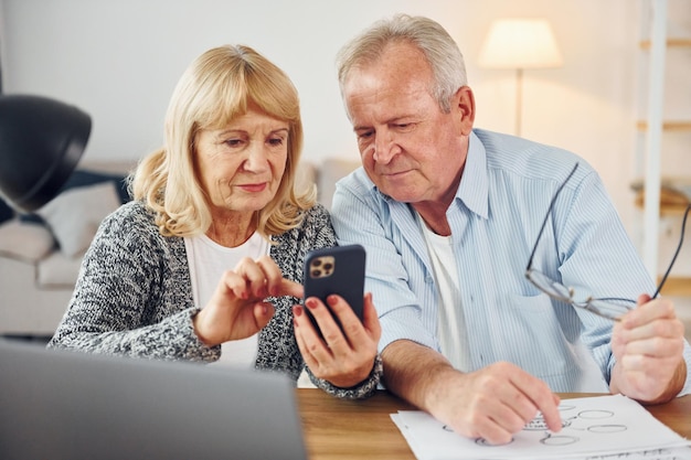 Foto mit laptop auf dem tisch senior mann und frau sind zusammen zu hause