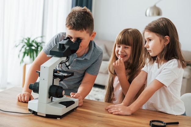 Mit Mikroskop Kinder, die sich tagsüber gemeinsam im Wohnzimmer vergnügen