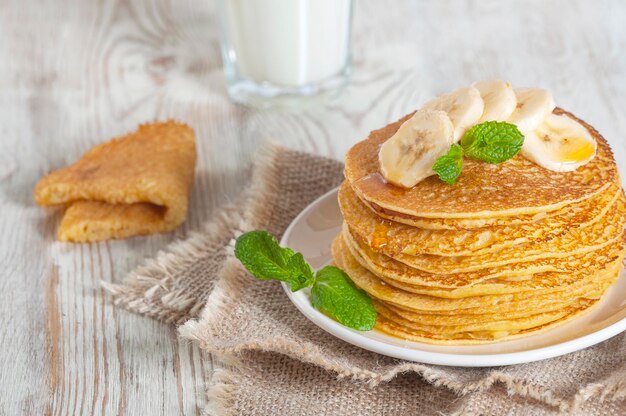 Mit Milch servierte Pfannkuchen, garniert mit Minzblättern und Bananenscheibenx