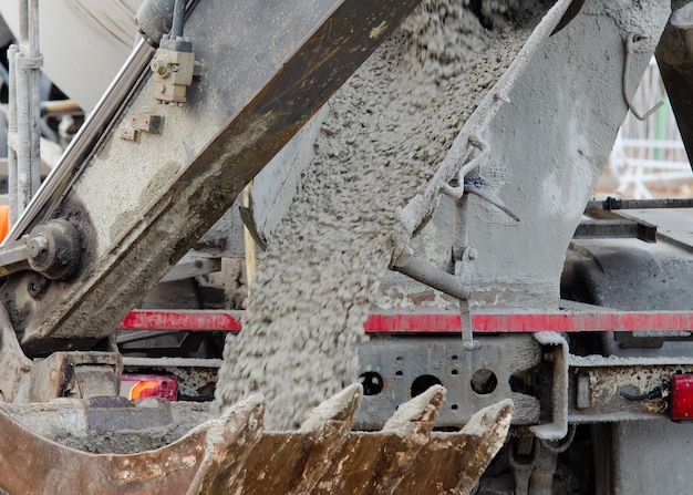 Foto mit nassem beton gefüllter baggereimer, um ihn zu betonarbeiten auf der baustelle zu bringen