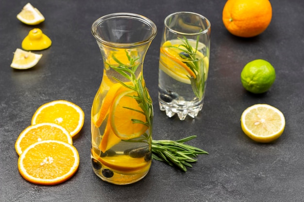 Mit Orangenheidelbeeren und Rosmarin angereichertes Wasser in Glas und Flasche