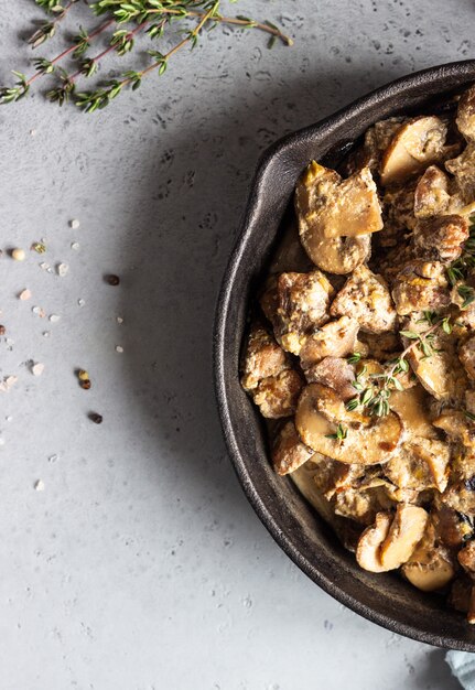 Foto mit pilz und thymian gedünstetes fleisch in einer gusseisernen pfanne