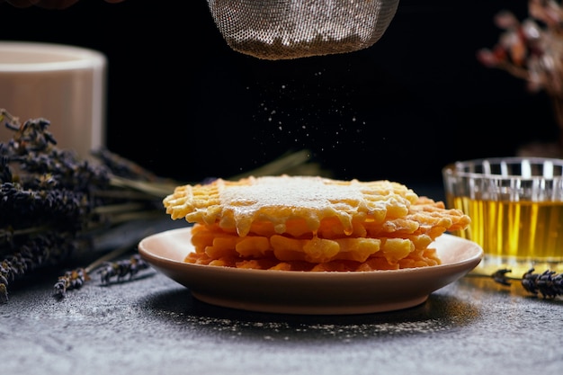 Mit Puderzucker bestreute Waffeln auf dunklem Hintergrund, Nahaufnahme