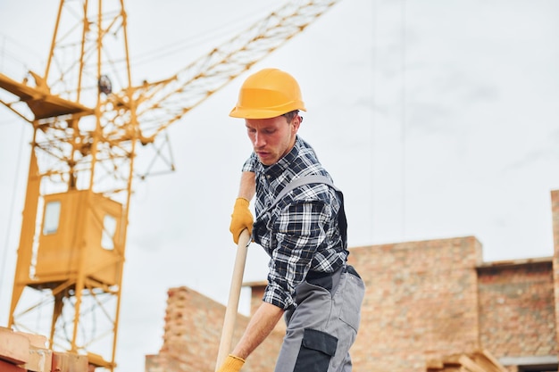 Mit Schaufel in den Händen Bauarbeiter in Uniform und Sicherheitsausrüstung haben Arbeit am Bau