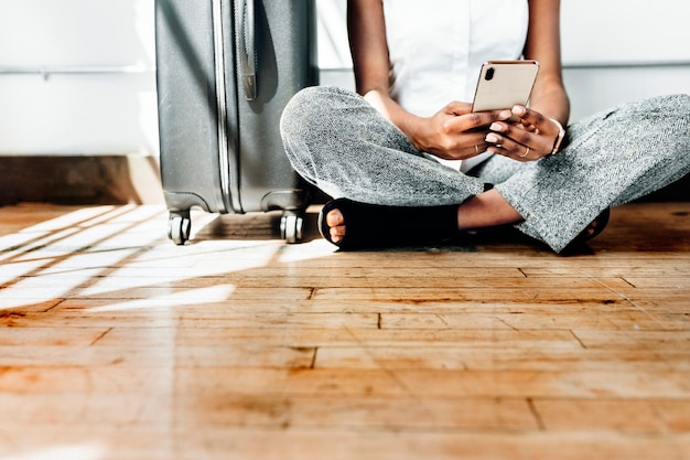 Mit Smartphone auf dem Boden sitzen