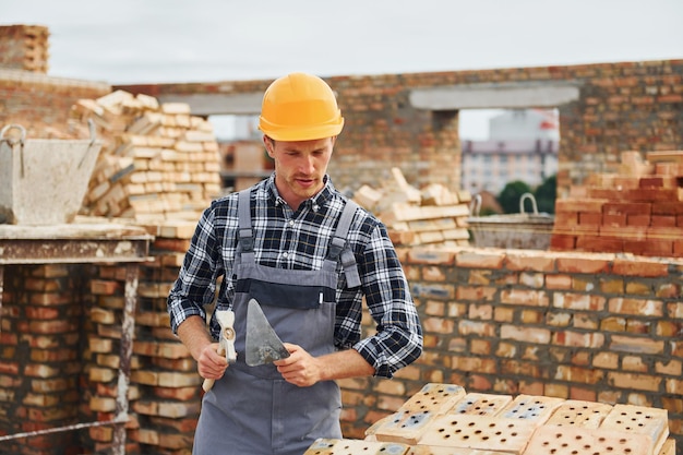 Mit Spachtel für Bauarbeiter in Uniform und Sicherheitsausrüstung haben Arbeit am Bau