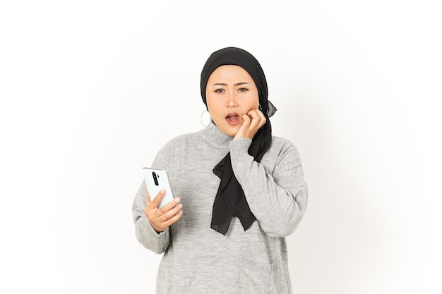 Mit Telefon und besorgt über schöne asiatische Frau mit Hijab isoliert auf weißem Hintergrund