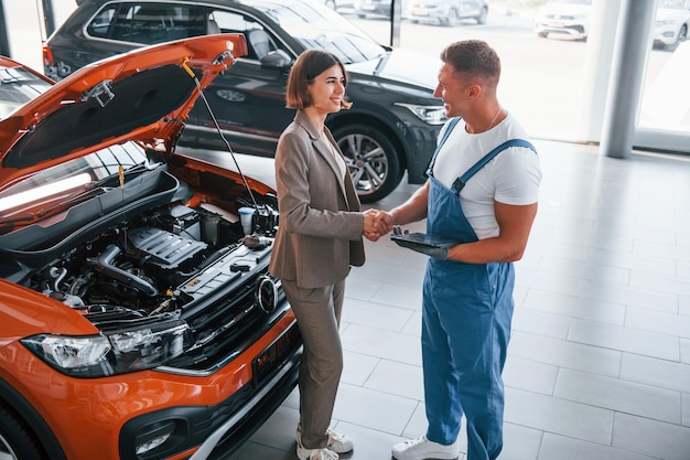 Mit weiblichen Kunden Mann, der das Auto der Frau im Innenbereich repariert Professioneller Service