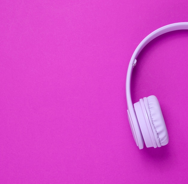 Foto la mitad de los auriculares morados sobre fondo rosa