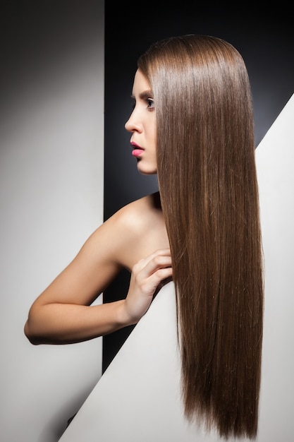 La mitad de la cara de la atractiva joven morena con el pelo largo y brillante