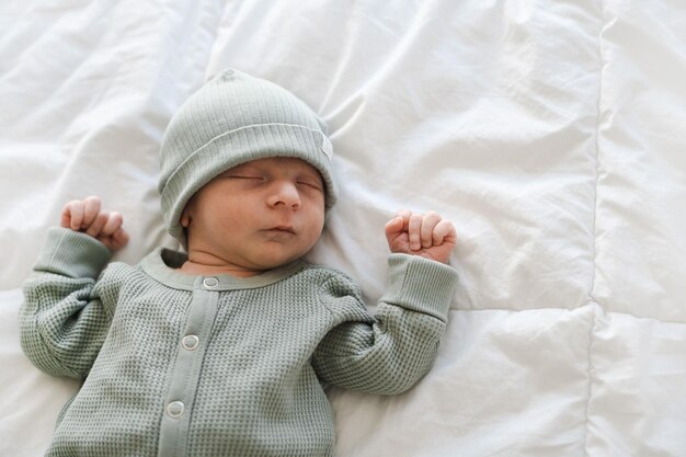 La mitad del cuerpo de la caucásica peluda morena bebé recién nacido lindo durmiendo con arrastradores verdes y capón
