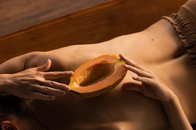 La mitad de la fruta de papaya en la espalda de la mujer. Pulpa de fruta tropical fragante. Dulce papaya fresca, comida crudivegana