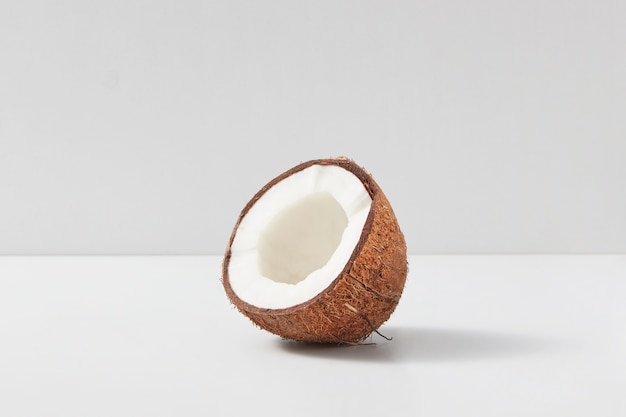 La mitad de la fruta tropical orgánica natural de coco maduro sobre un fondo duotono gris claro, copie el espacio. Concepto vegetariano.