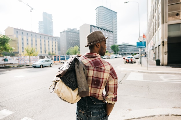 La mitad de la longitud del joven afro negro guapo caminando en la calle de la ciudad