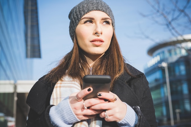 La mitad de longitud de joven hermosa mujer caucásica sosteniendo un teléfono inteligente