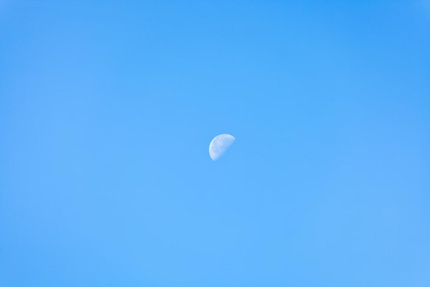 La mitad de la luna en el cielo azul claro de la mañana