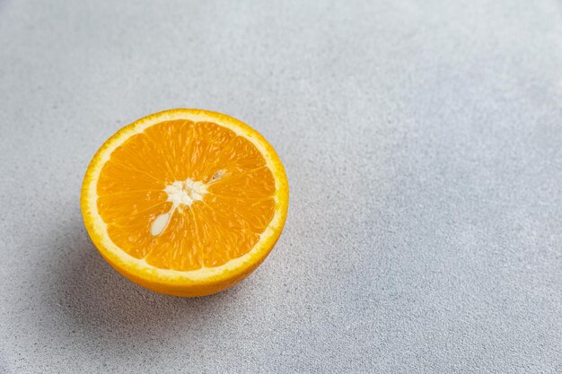La mitad de una naranja sobre un fondo gris.