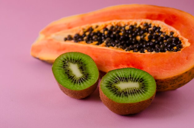 La mitad de papaya fresca madura y kiwi en rosa