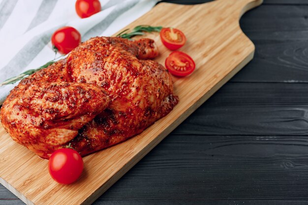 La mitad de pollo a la plancha sobre tabla de cortar de madera cerrar