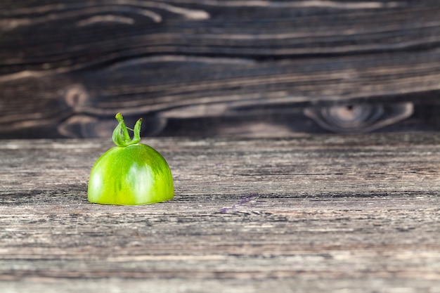 La mitad de un tomate verde sobre una placa pintada de negro, primer plano