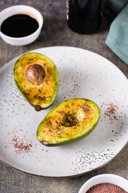 Mitades de aguacate con sal negra del Himalaya en un plato sobre la mesa Vista vertical