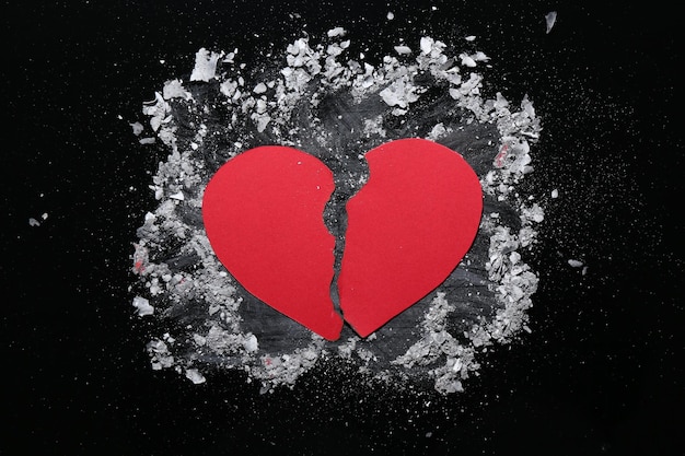 Mitades de corazón de papel rasgado y ceniza en fondo negro vista superior