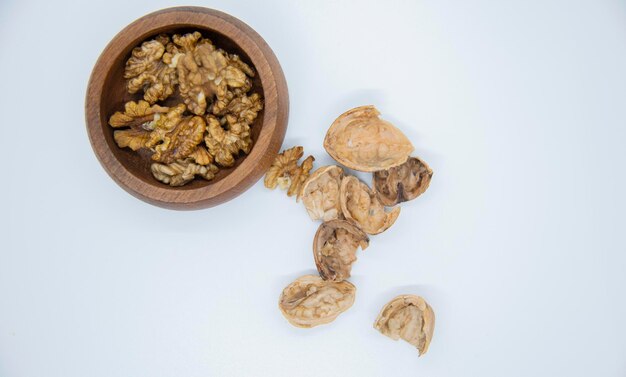 Las mitades del grano de nuez en un cuenco de madera en un primer plano de fondo blanco