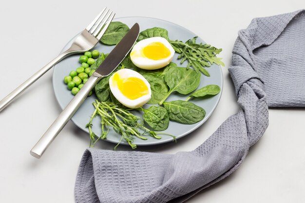 mitades de huevo de gallina hervido hojas de espinaca rúcula y guisantes verdes