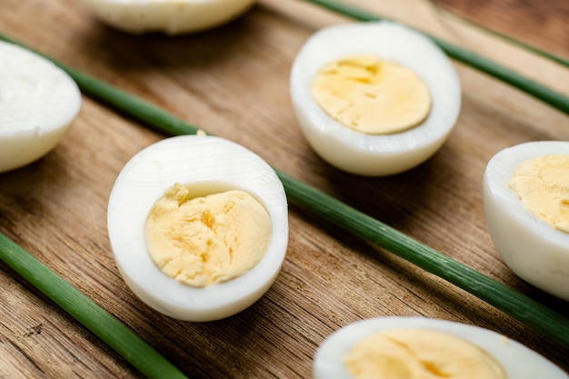 Mitades de huevos de gallina cocidos con vainas de cebolla verde sobre un fondo de madera.